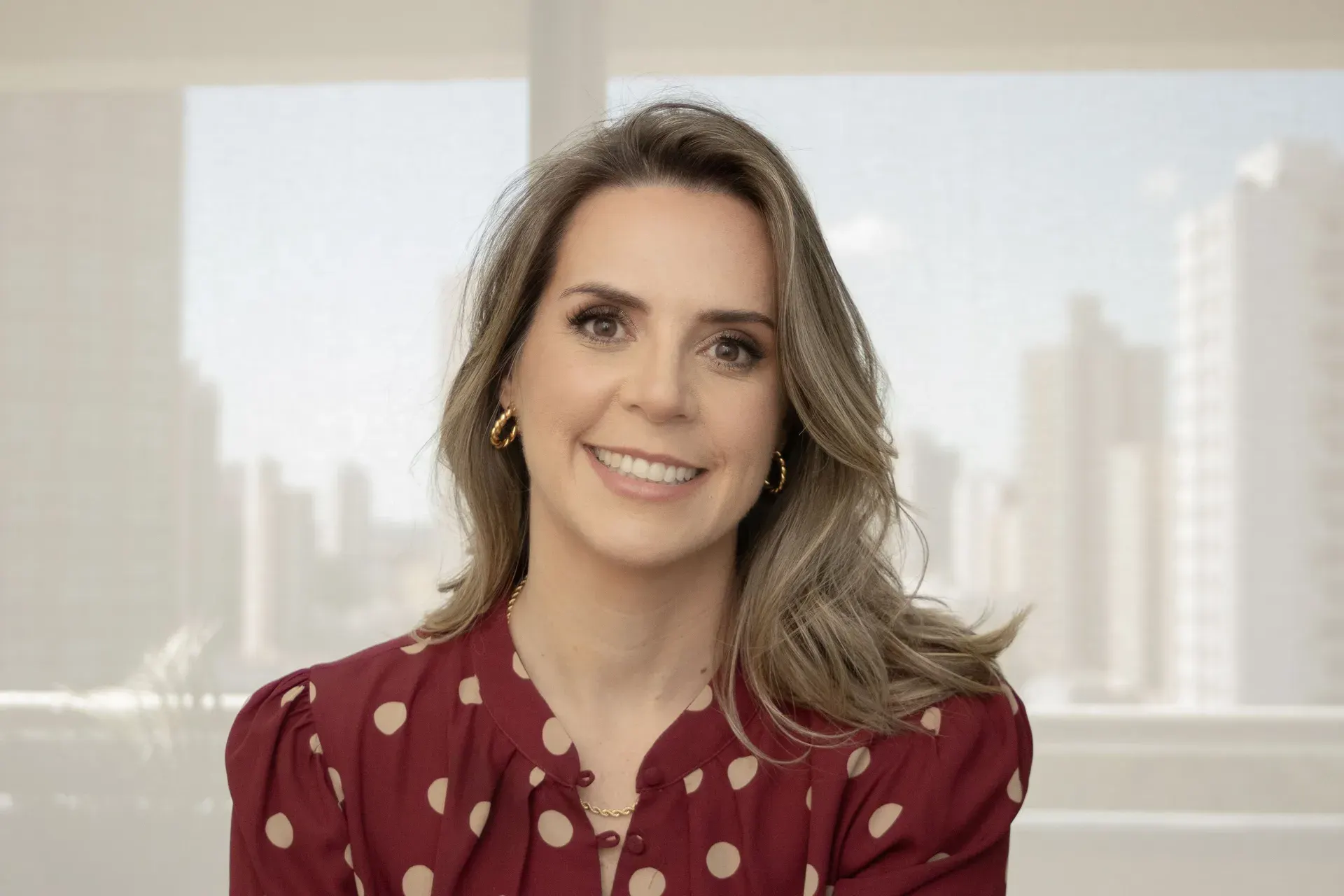 Dra. Aline De Bortoli, geriatra, sorrindo em seu consultório em Jundiaí